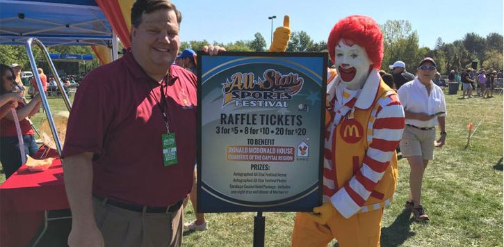 a man standing in front of a raffle ticket sign with Ronald McDonald