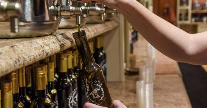 a person pouring out olive oil