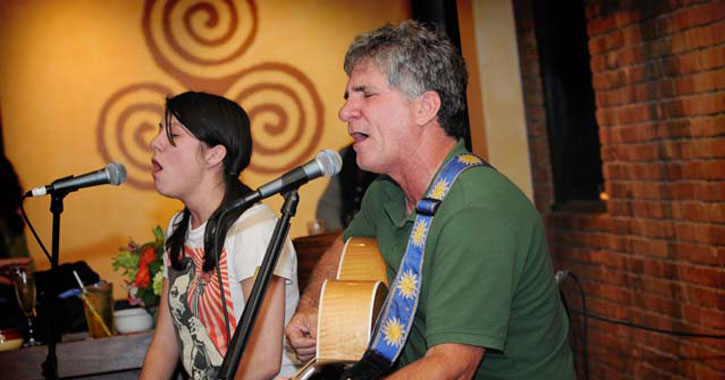 a young woman and older man performing music together on stage